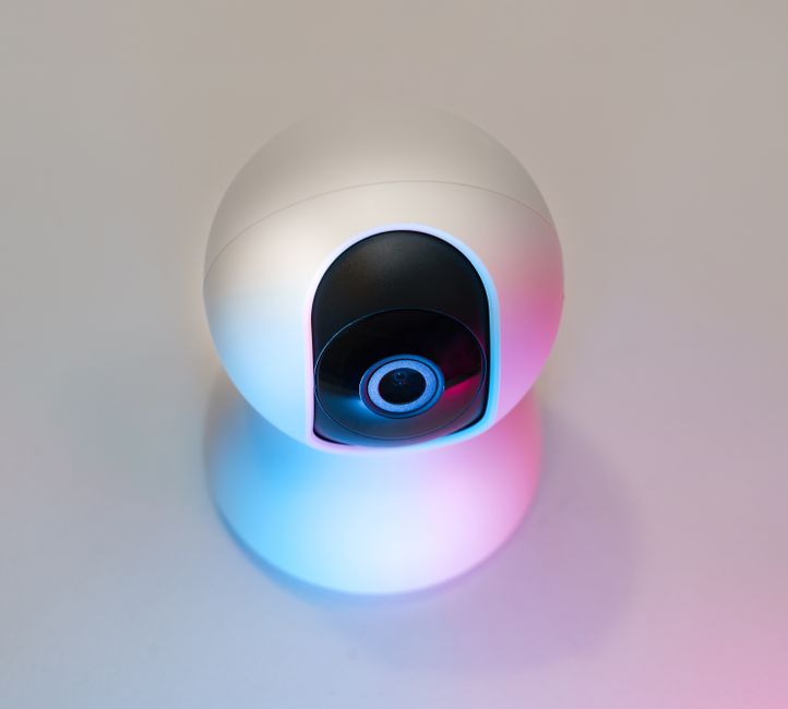 A sleek, modern security camera highlighted by blue and pink lighting, symbolizing advanced surveillance technology.